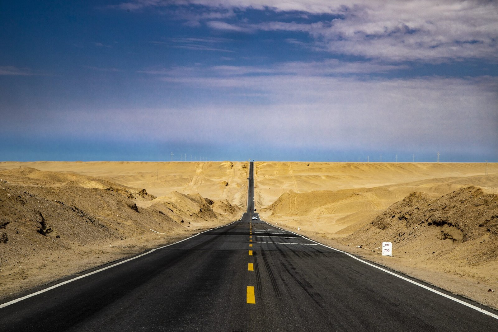 Long straight asphalt road stretching into the distant horizon through an open desert landscape under a clear blue sky, symbolizing forward direction and decisive action.